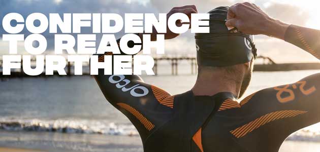 A younger athlete preparing to swim in an Orca wetsuit