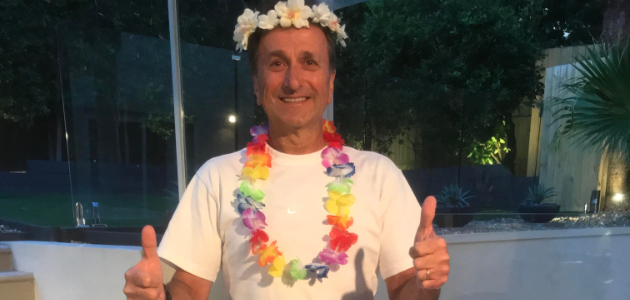 Mario Staffieri smiling in a white T-shirt and Hawaiian leis before racing in Kona